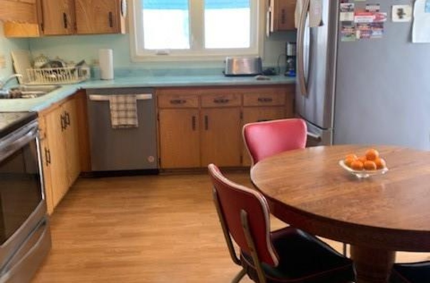 Kitchen with stove, sink, light hardwood / wood-style flooring, fridge, and dishwashing machine