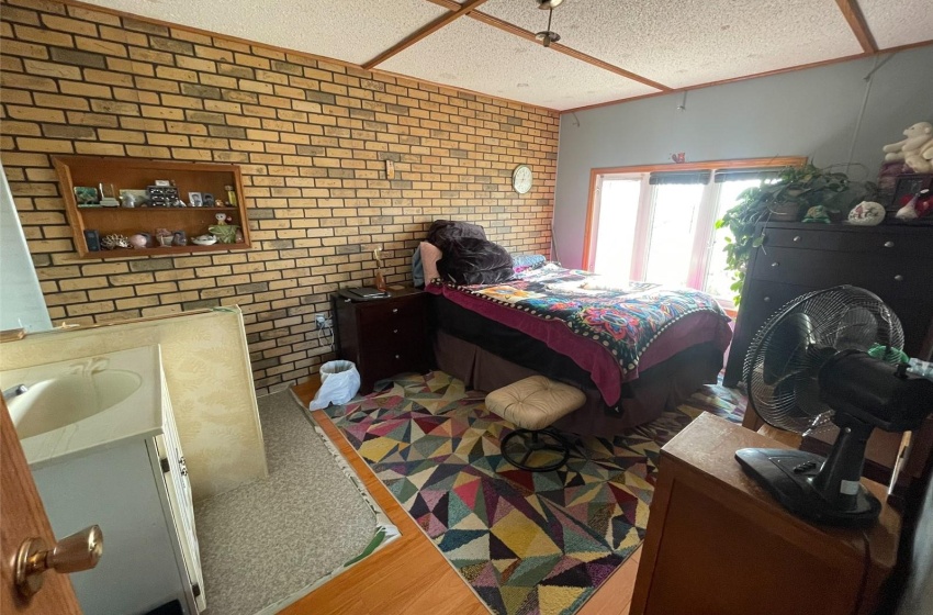 Bedroom with hardwood / wood-style floors, sink, and brick wall