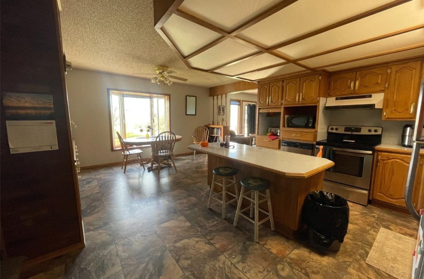 Kitchen with black microwave, stainless steel electric range oven, a center island, ceiling fan, and a kitchen breakfast bar