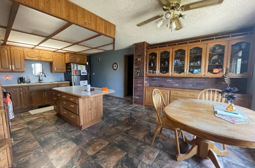 Kitchen featuring ceiling fan, a center island, sink, stainless steel fridge, and a textured ceiling