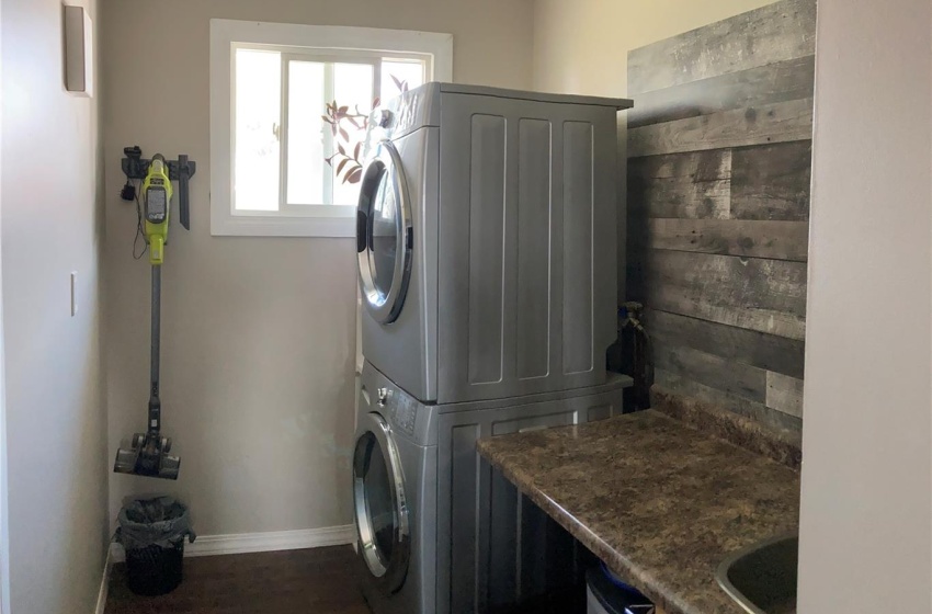 Washroom with dark hardwood / wood-style floors and stacked washer and dryer