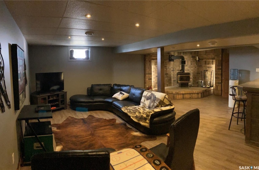 Living room with a paneled ceiling, a wood stove, and light hardwood / wood-style flooring