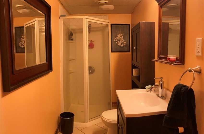 Bathroom with a shower with shower door, tile floors, toilet, a drop ceiling, and oversized vanity