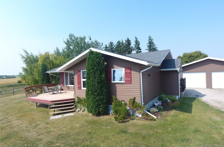 View of side of home with a yard, a deck, an outdoor structure, and a garage