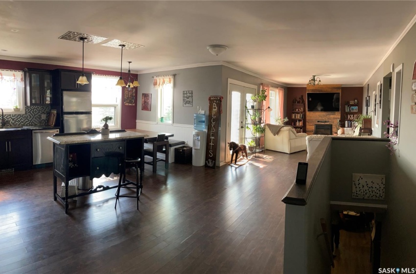 Kitchen with stainless steel appliances, decorative light fixtures, dark wood-type flooring, sink, and a breakfast bar area