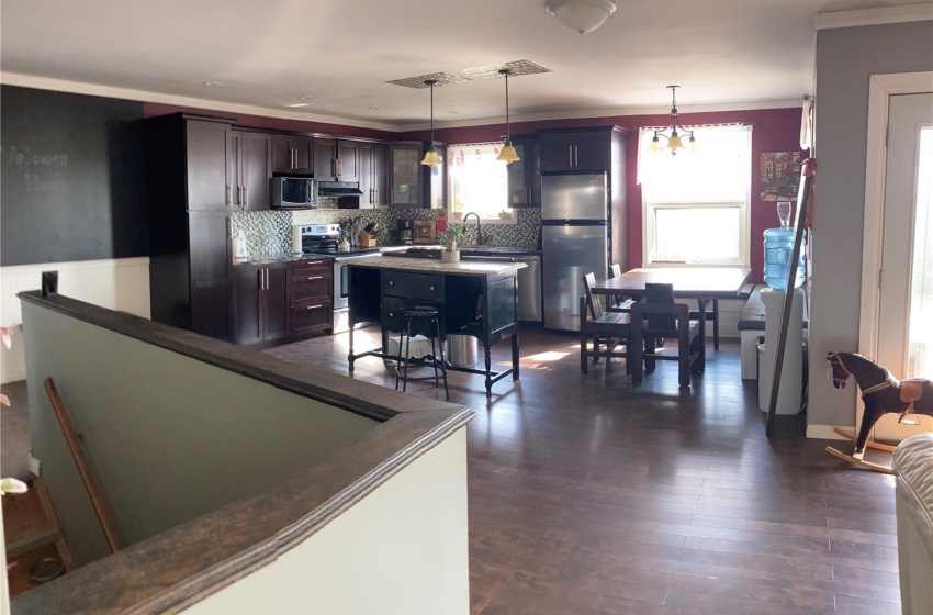 Kitchen featuring dark brown cabinets, stainless steel appliances, dark hardwood / wood-style flooring, backsplash, and hanging light fixtures