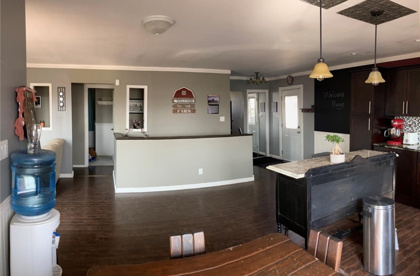 Kitchen with dark hardwood / wood-style floors, dark brown cabinets, crown molding, hanging light fixtures, and a center island