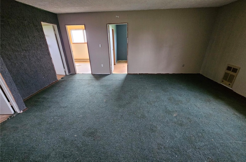 Empty room with a textured ceiling and dark carpet