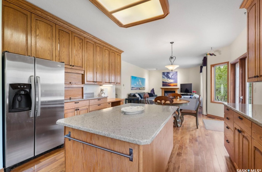 Kitchen with stainless steel fridge, a center island, hanging light fixtures, and light hardwood / wood-style floors