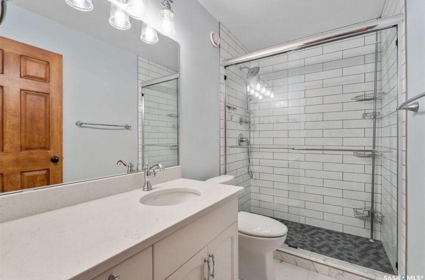 Bathroom featuring tile patterned flooring, toilet, vanity, and an enclosed shower