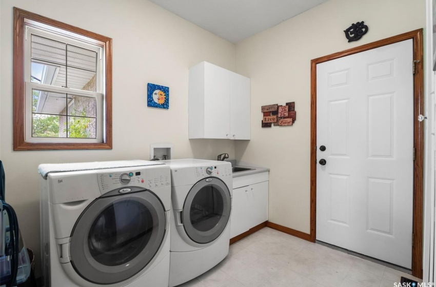 Washroom featuring sink, cabinets, washer and clothes dryer, and light tile patterned floors