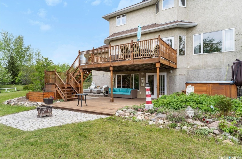 Rear view of property with a lawn, a patio, an outdoor living space, a deck, and a hot tub