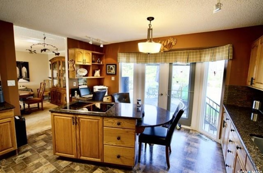 Kitchen featuring black electric stovetop, a textured ceiling, decorative light fixtures, and rail lighting