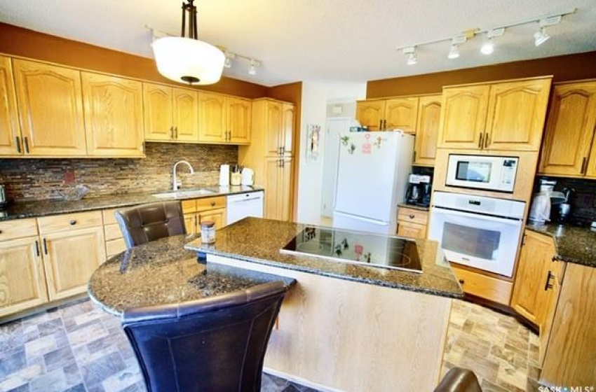 Kitchen with a kitchen island, sink, white appliances, and backsplash