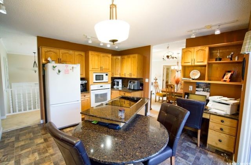 Kitchen featuring decorative light fixtures, a center island, dark tile flooring, track lighting, and white appliances