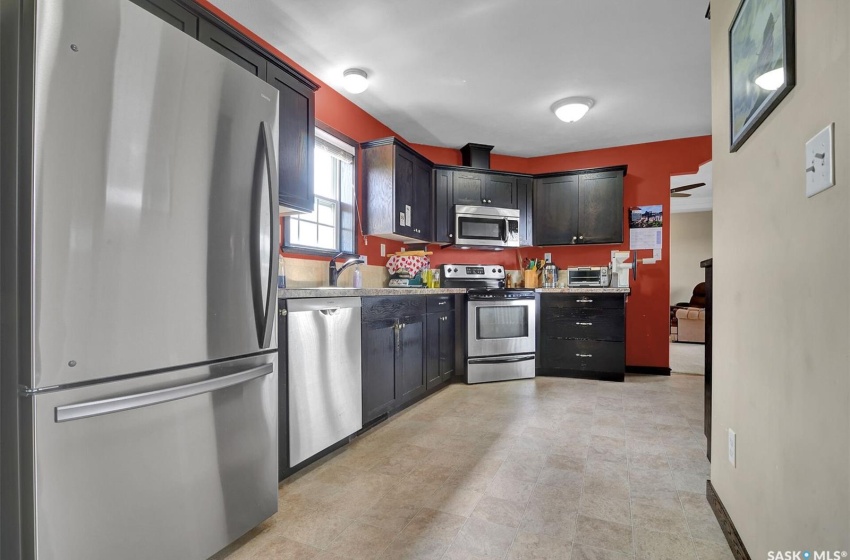 Kitchen featuring sink, dark brown cabinets, light tile floors, and stainless steel appliances