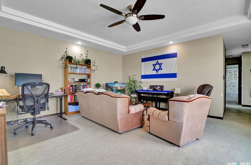 Living room featuring carpet, ceiling fan, and a raised ceiling