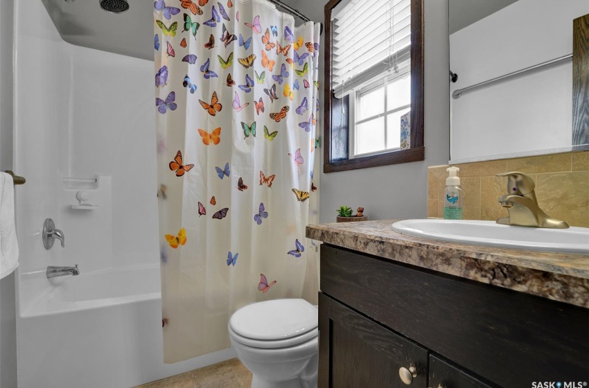 Full bathroom featuring backsplash, shower / bath combination with curtain, toilet, and large vanity