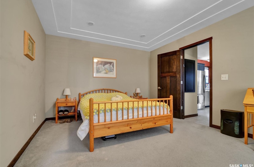 Carpeted bedroom featuring stainless steel refrigerator