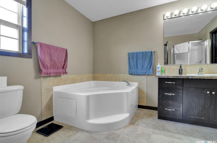 Bathroom with tile flooring, a tub, tile walls, vanity, and toilet