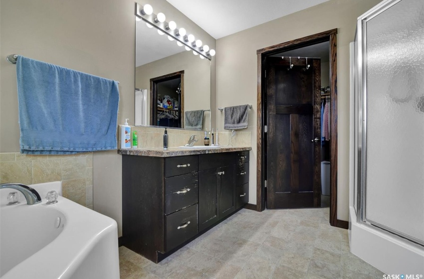 Bathroom featuring tile flooring, vanity with extensive cabinet space, a bathing tub, and tile walls