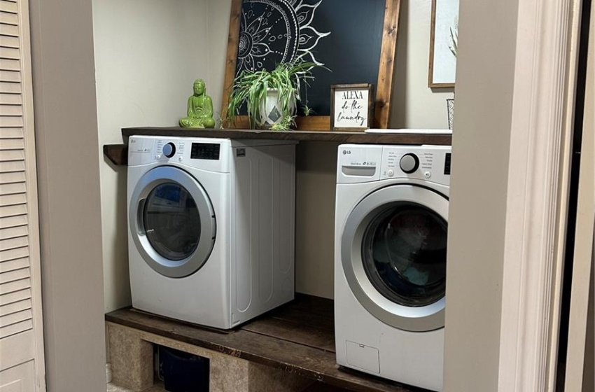 Laundry room featuring a textured ceiling, carpet floors, and washer and clothes dryer