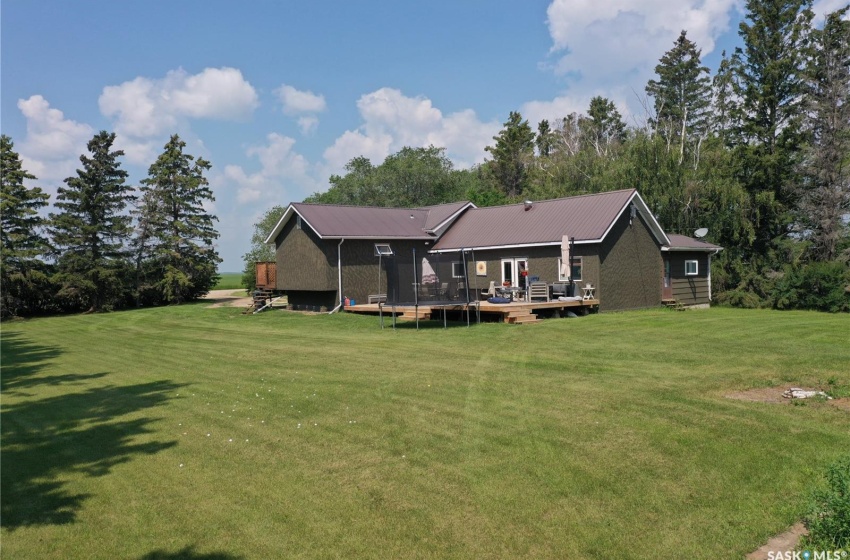 Rear view of house featuring a lawn, a trampoline, and a wooden deck