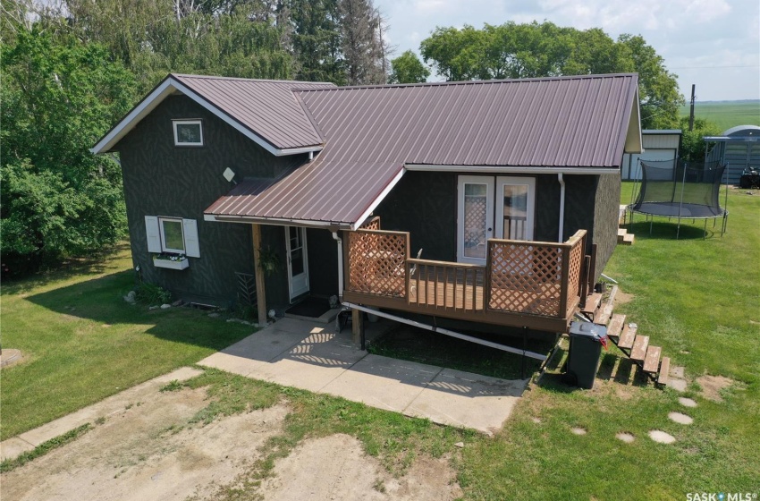 View of front of home with a deck, a trampoline, and a front lawn