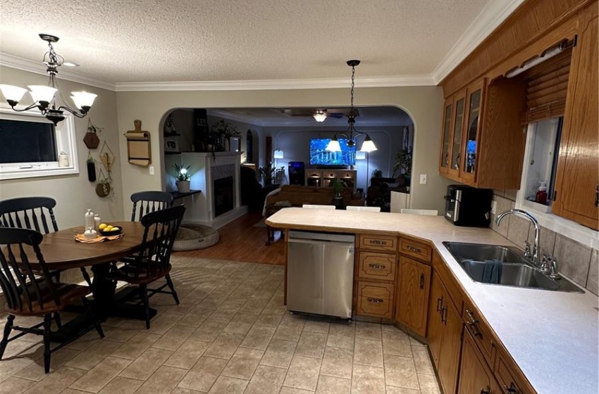 Kitchen featuring ornamental molding, kitchen peninsula, a chandelier, sink, and dishwasher