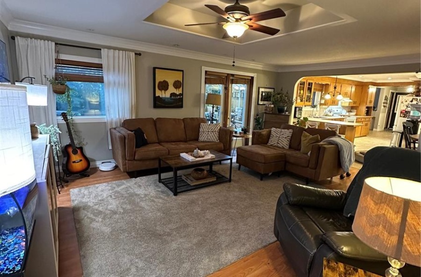 Carpeted living room featuring ceiling fan, a tray ceiling, and french doors