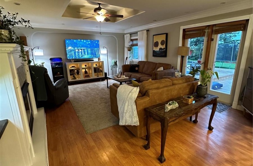 Living room with ceiling fan, a tray ceiling, a textured ceiling, and hardwood / wood-style flooring