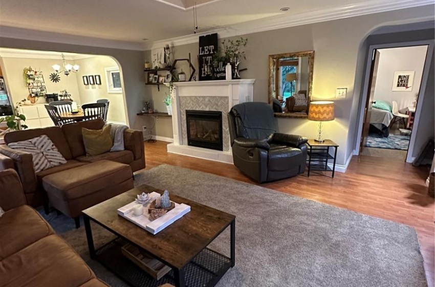 Living room with hardwood / wood-style floors, ceiling fan, a tray ceiling, and crown molding