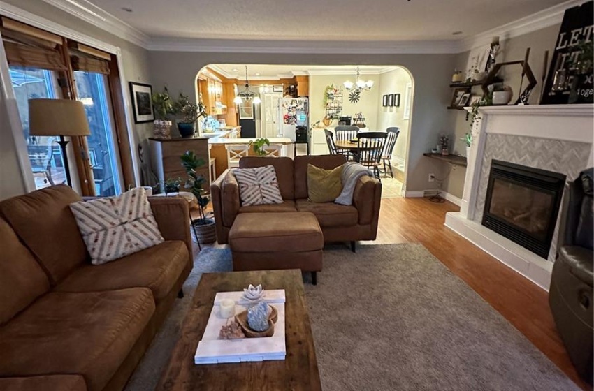 Living room with a tray ceiling, ornamental molding, wood-type flooring, and ceiling fan