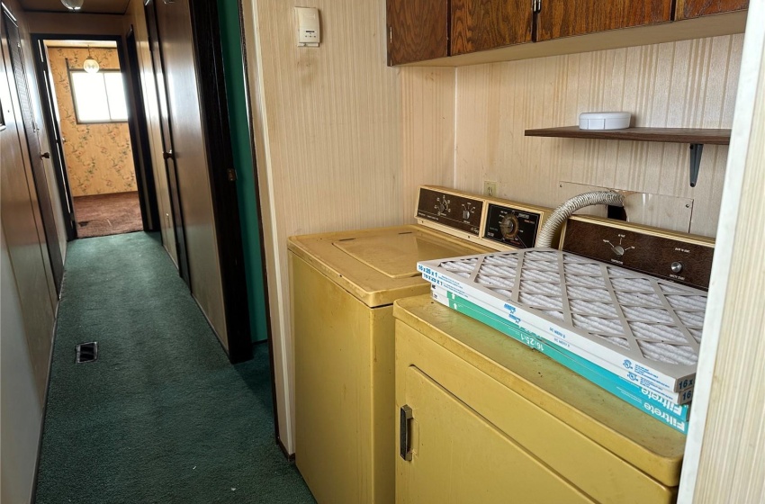 Clothes washing area featuring carpet, cabinets, and washer and dryer