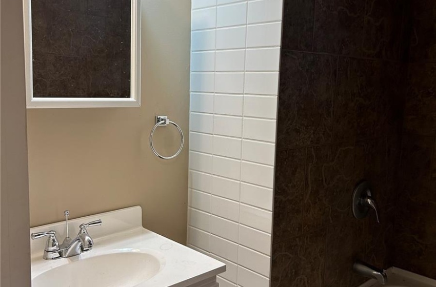 Bathroom with tiled shower / bath combo and vanity