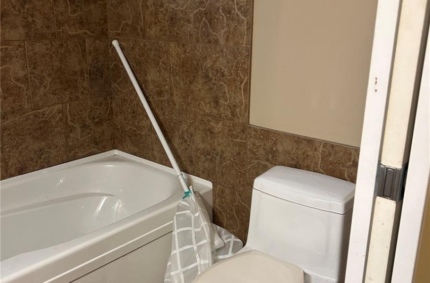 basement Bathroom with toilet, tile patterned flooring, and tile walls