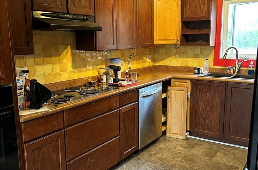 Kitchen featuring light tile patterned floors, black oven, dishwasher, track lighting, and sink