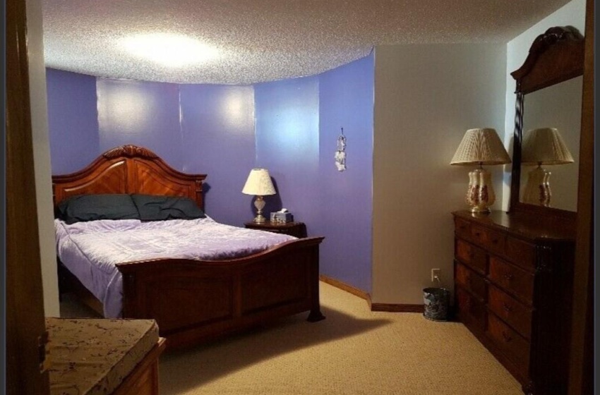 Bedroom with a textured ceiling and light colored carpet