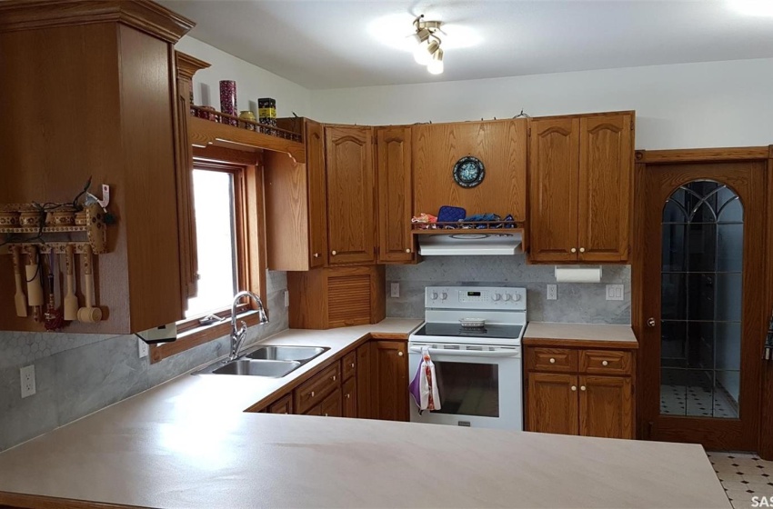 Kitchen featuring tasteful backsplash, kitchen peninsula, sink, and white electric stove