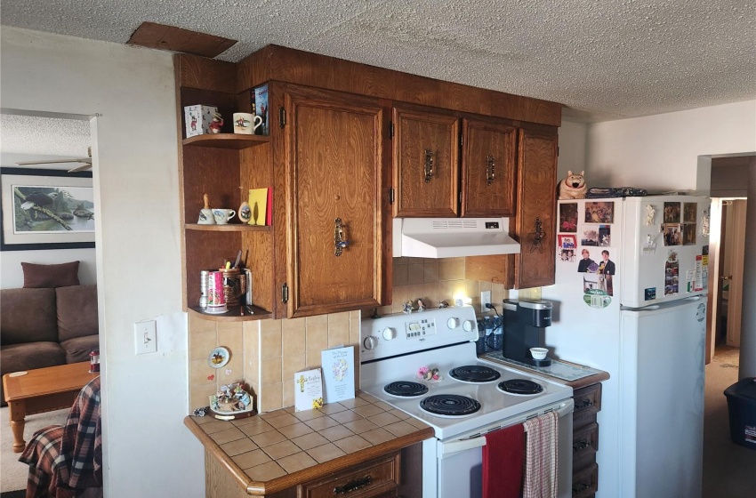 Kitchen featuring white appliances, tile counters, a textured ceiling, and tasteful backsplash