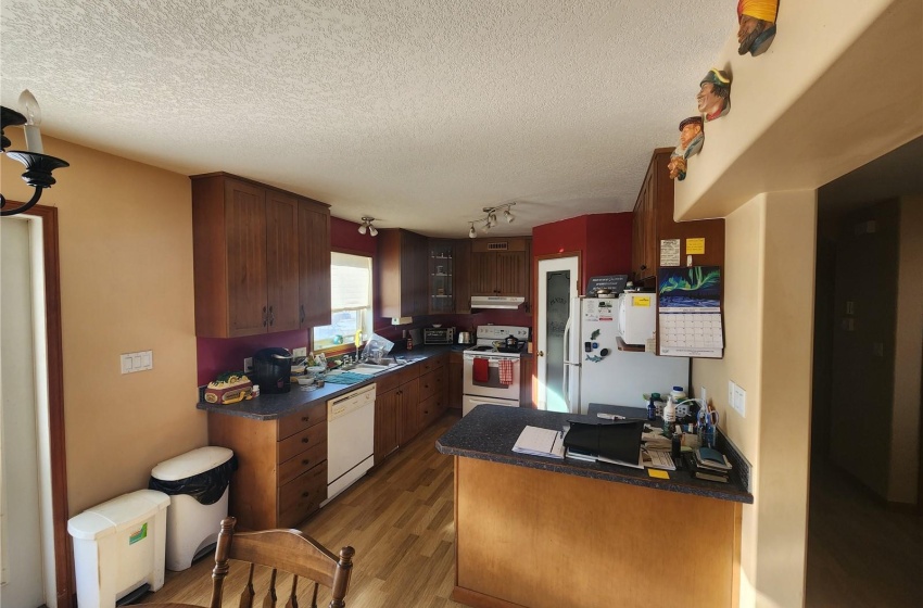 Kitchen featuring white appliances, track lighting, a textured ceiling, and light hardwood / wood-style floors