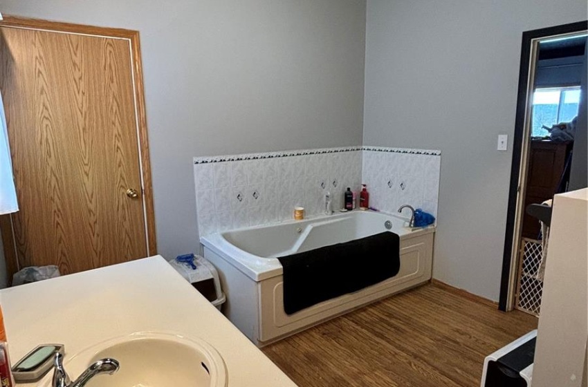 Bathroom featuring hardwood / wood-style floors, vanity, a tub to relax in, and vaulted ceiling