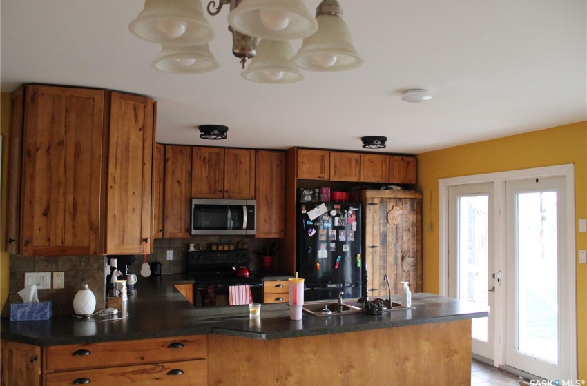 Kitchen featuring black appliances, kitchen peninsula, decorative backsplash, and plenty of natural light