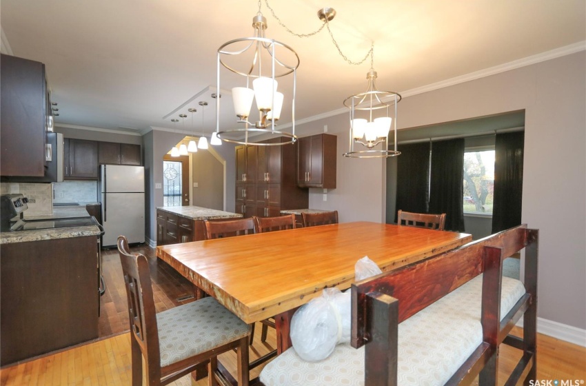 Dining area featuring a notable chandelier, light wood-type flooring, and crown molding