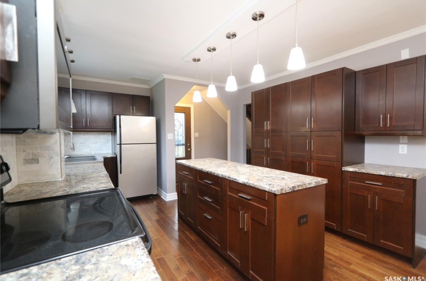 Kitchen featuring white refrigerator, pendant lighting, dark wood-type flooring, and range