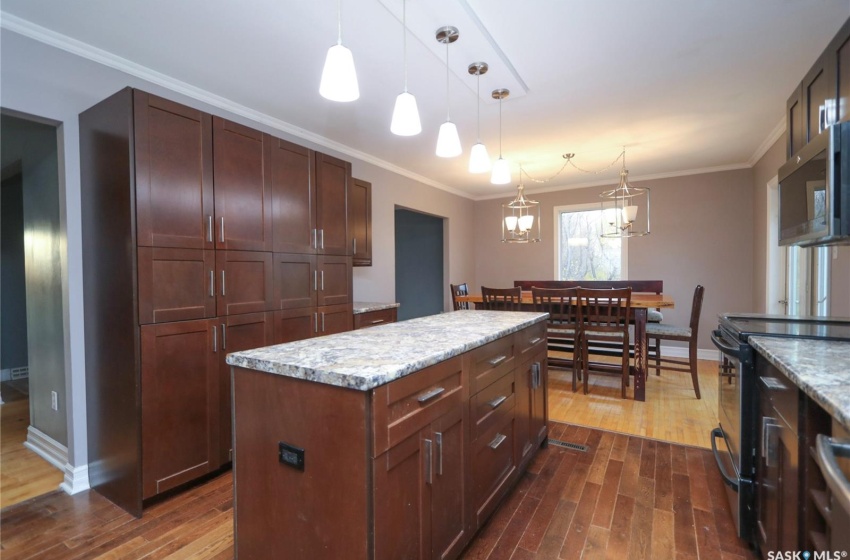 Kitchen with dark wood-type flooring, hanging light fixtures, black electric range oven, and a kitchen island