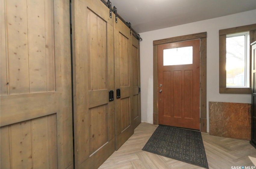 Doorway to outside with light parquet floors and a barn door