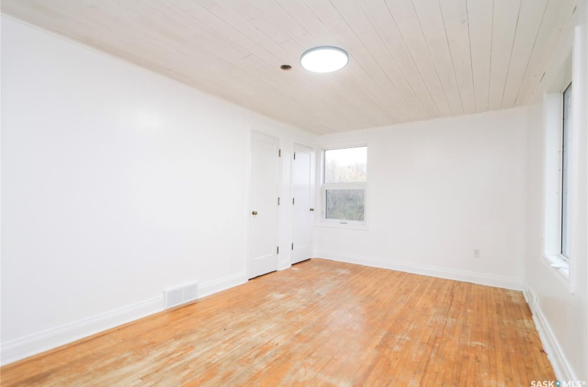 Empty room with wooden ceiling and light wood-type flooring