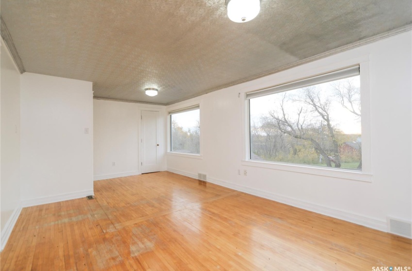 Empty room featuring plenty of natural light, hardwood / wood-style floors, and a textured ceiling