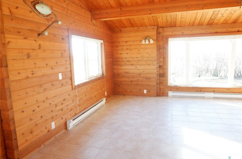 Empty room with a baseboard heating unit, wooden walls, and plenty of natural light